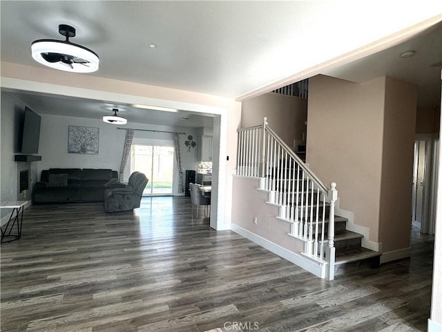 entryway featuring a fireplace, dark wood finished floors, stairway, and baseboards