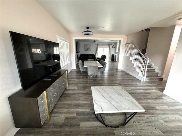 living room with dark wood-style flooring, baseboards, and stairs