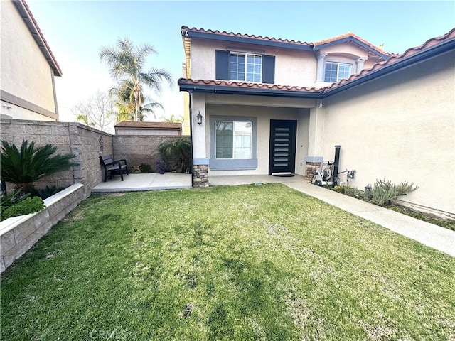 exterior space with a lawn, a tile roof, fence, a patio area, and stucco siding