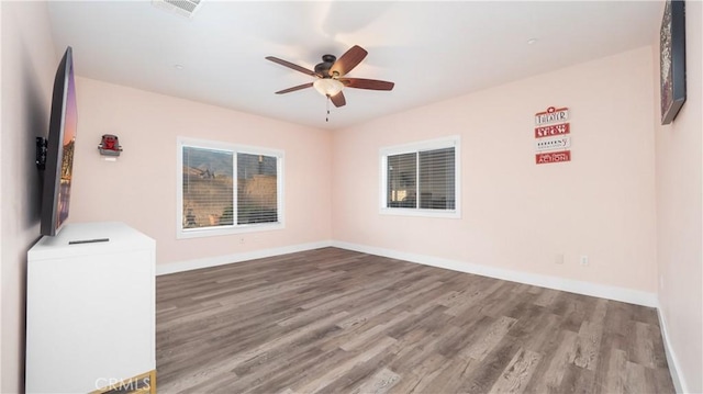 spare room with visible vents, baseboards, and wood finished floors