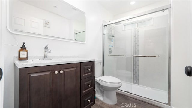 bathroom with toilet, a stall shower, wood finished floors, and vanity