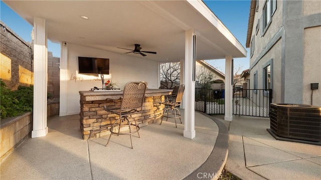 view of patio / terrace with ceiling fan, cooling unit, outdoor wet bar, and fence