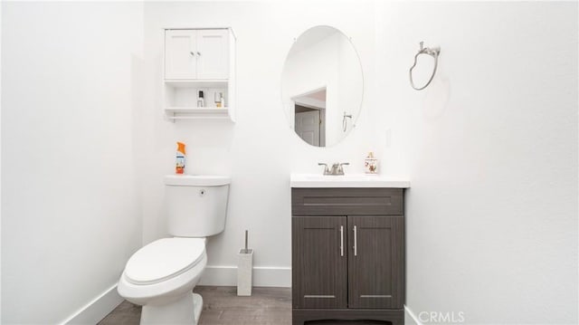 bathroom featuring wood finished floors, vanity, toilet, and baseboards