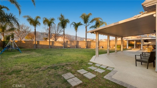 view of yard with a patio, a playground, a fenced backyard, and a mountain view