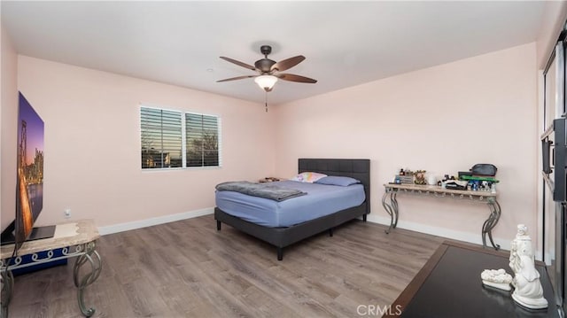 bedroom with a ceiling fan, baseboards, and wood finished floors