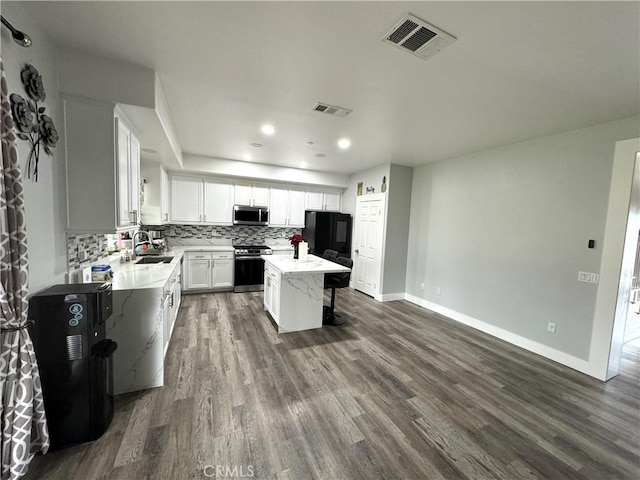 kitchen featuring dark wood-style floors, appliances with stainless steel finishes, backsplash, and visible vents