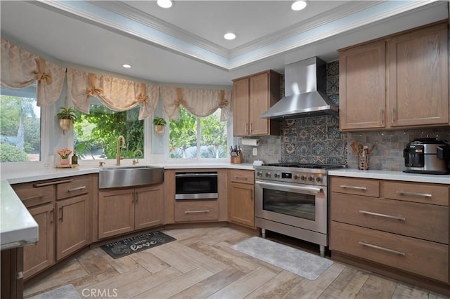 kitchen with sink, backsplash, a tray ceiling, gas stove, and wall chimney range hood