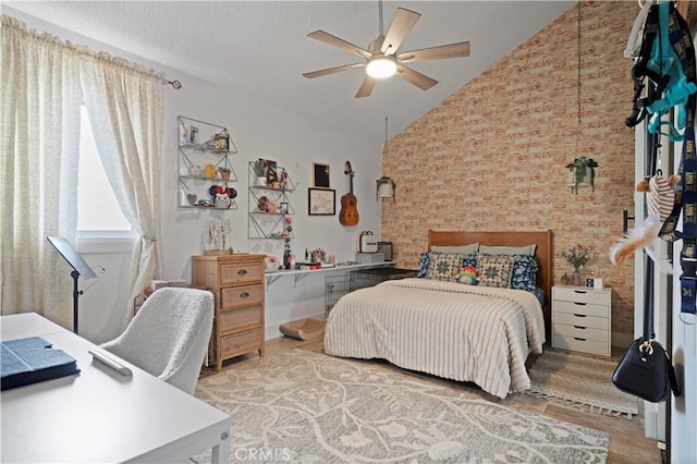 bedroom featuring ceiling fan, lofted ceiling, wood-type flooring, and a textured ceiling