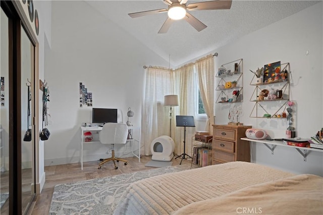 bedroom featuring lofted ceiling, ceiling fan, light hardwood / wood-style flooring, and a textured ceiling