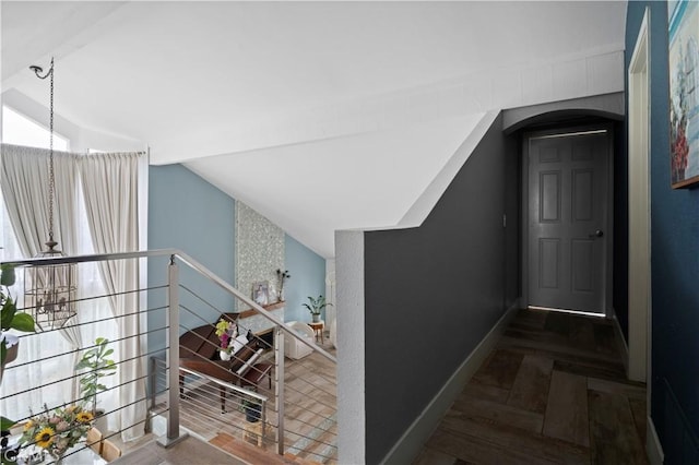 staircase featuring an inviting chandelier, parquet flooring, and vaulted ceiling