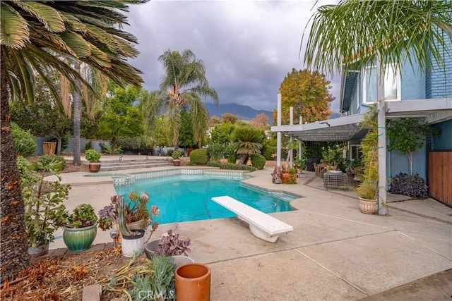 view of pool with a patio, a pergola, a mountain view, and a diving board