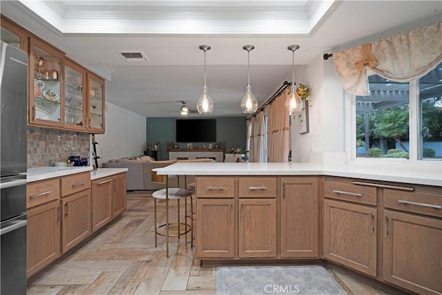 kitchen featuring a breakfast bar, pendant lighting, stainless steel fridge, backsplash, and light parquet floors