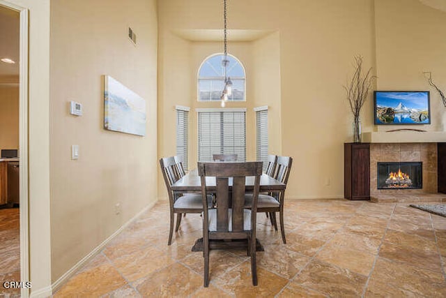 dining area with a towering ceiling and a tile fireplace