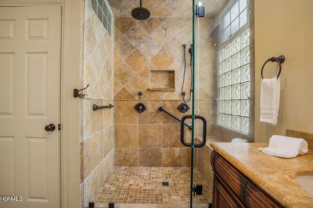 bathroom featuring vanity, a shower with shower door, and a healthy amount of sunlight