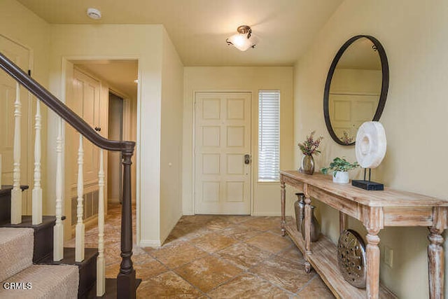 foyer entrance with stairs and baseboards