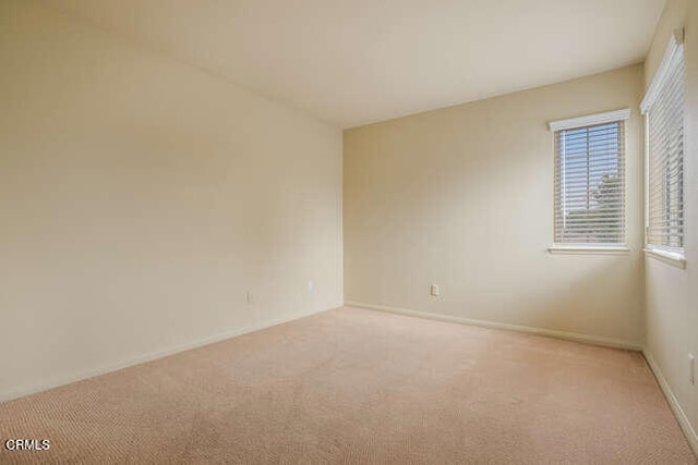 unfurnished room with baseboards and light colored carpet