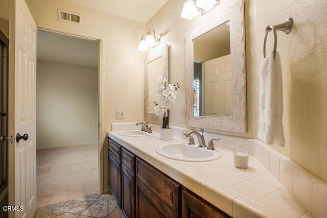 bathroom with double vanity, a sink, visible vents, and tile patterned floors