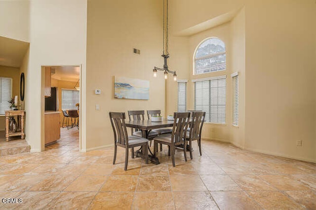 dining room with a high ceiling, visible vents, and a chandelier