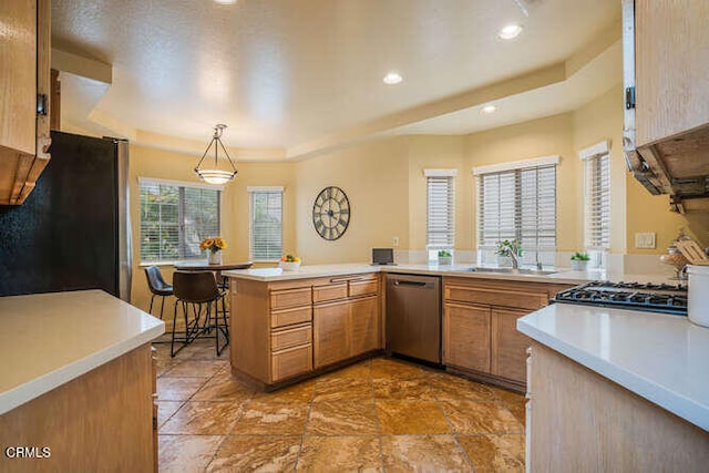 kitchen with a peninsula, stainless steel appliances, light countertops, and decorative light fixtures