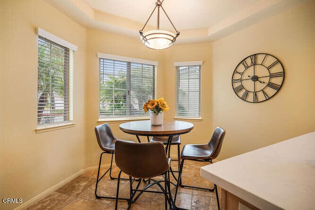 dining room featuring a tray ceiling and baseboards