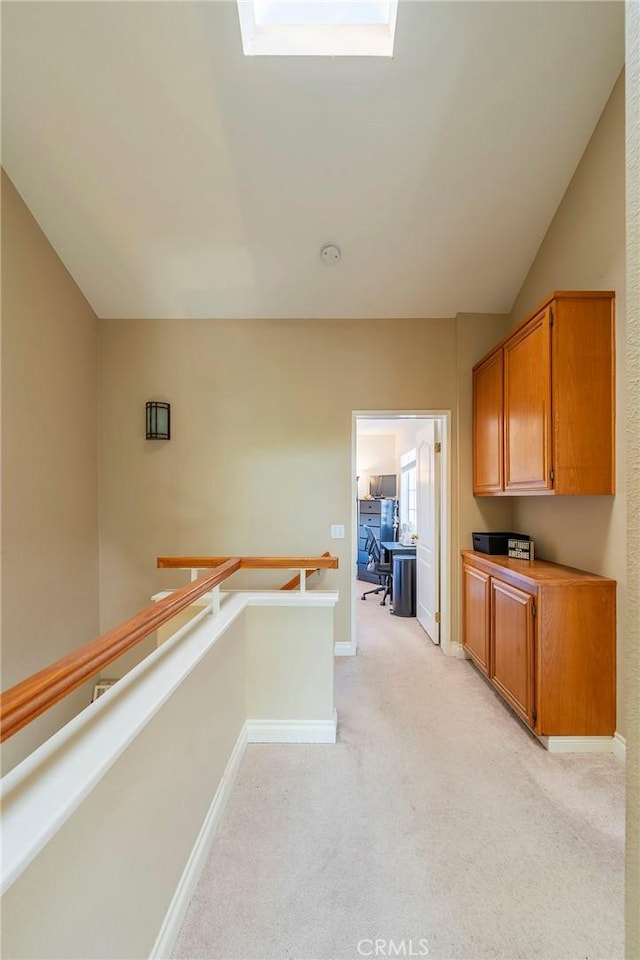 kitchen with light colored carpet and vaulted ceiling with skylight