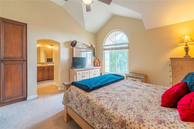 bedroom featuring ceiling fan, light colored carpet, vaulted ceiling, and ensuite bath