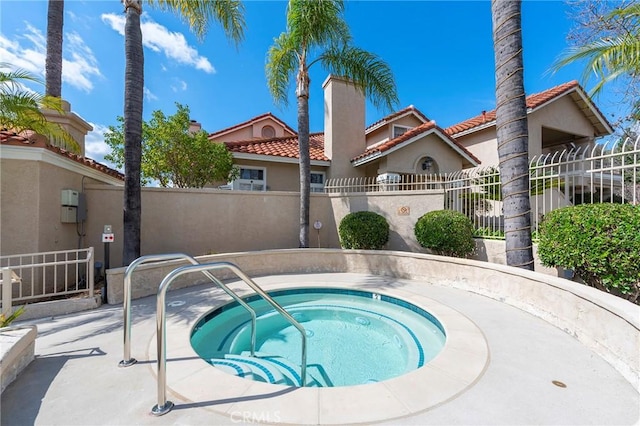 view of swimming pool with fence and a hot tub