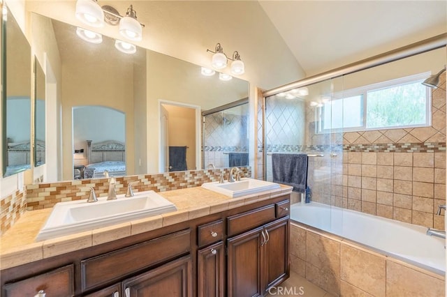 bathroom with vaulted ceiling, vanity, shower / bath combination with glass door, and decorative backsplash