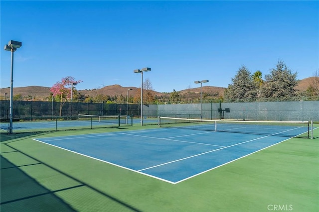 view of tennis court featuring fence and a mountain view