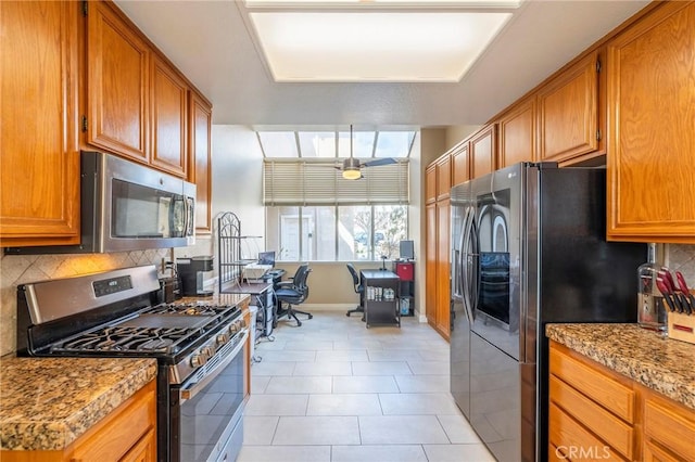 kitchen featuring tasteful backsplash, light tile patterned flooring, light stone countertops, and appliances with stainless steel finishes