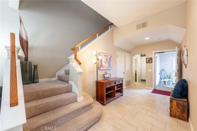 foyer with lofted ceiling, baseboards, stairs, and visible vents