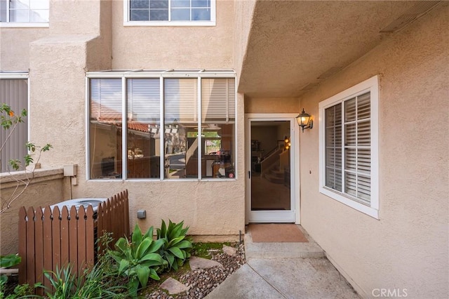 property entrance featuring fence and stucco siding