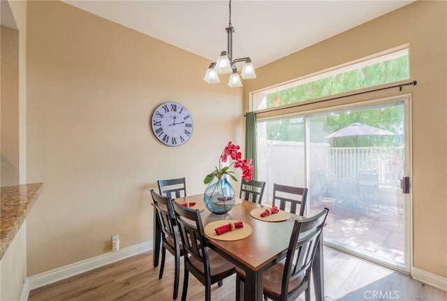 dining space with light wood-style flooring, baseboards, and a notable chandelier