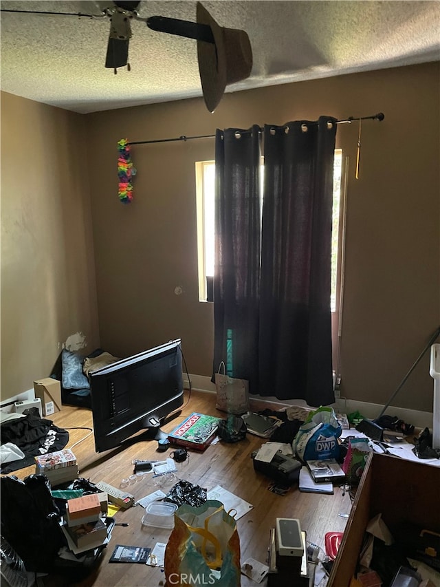 bedroom featuring ceiling fan, hardwood / wood-style floors, and a textured ceiling