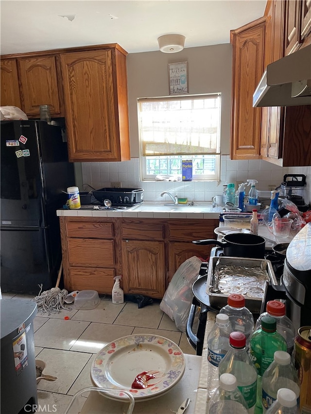 kitchen featuring black refrigerator, light tile patterned floors, decorative backsplash, and tile countertops