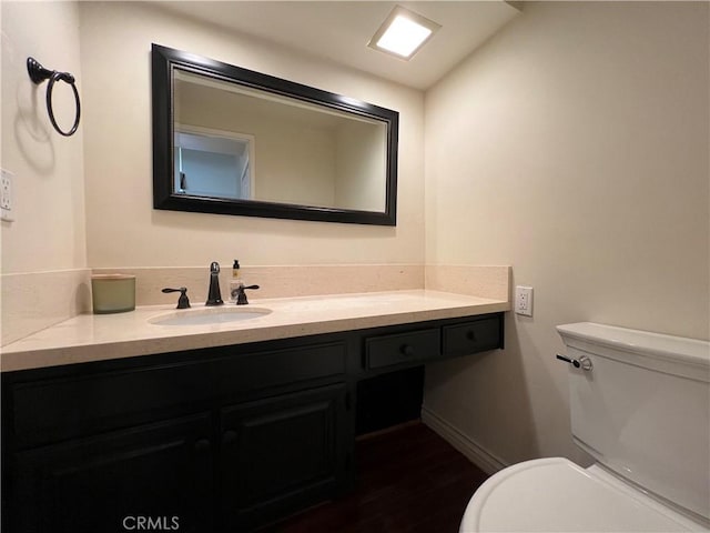 bathroom featuring vanity, toilet, and baseboards