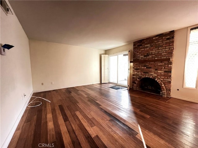 unfurnished living room with visible vents, a brick fireplace, baseboards, and hardwood / wood-style flooring