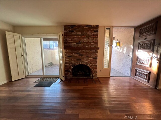 living room with a brick fireplace, wood finished floors, and baseboards