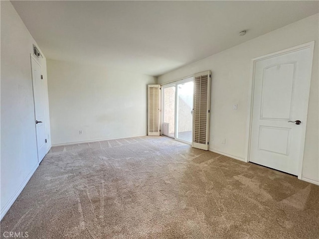 unfurnished bedroom featuring access to exterior, carpet, and baseboards