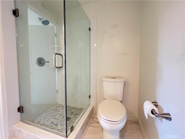 bathroom featuring toilet, baseboards, a stall shower, and marble finish floor