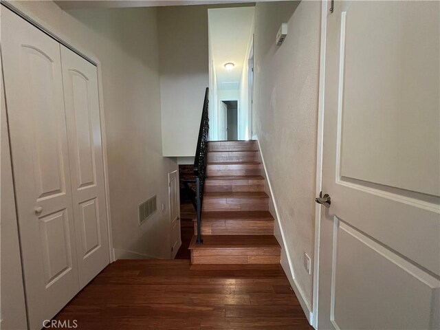 staircase featuring visible vents, baseboards, and wood finished floors