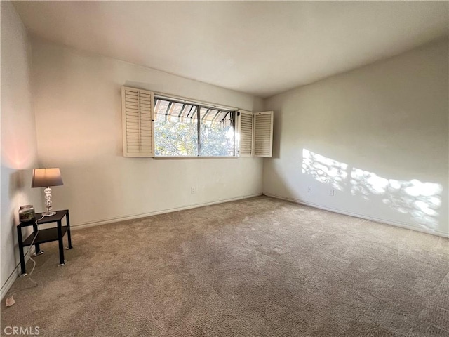 carpeted empty room featuring baseboards