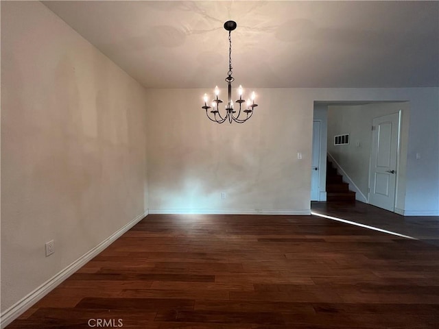 spare room featuring wood finished floors, baseboards, visible vents, stairs, and a chandelier