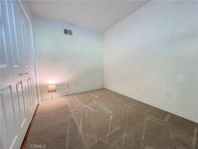 carpeted spare room featuring visible vents and baseboards