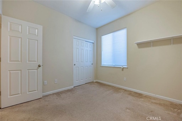 unfurnished bedroom with ceiling fan, a closet, and light carpet