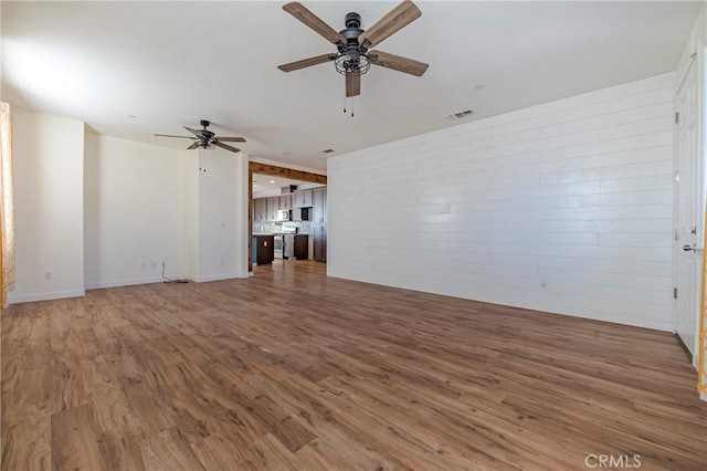 unfurnished living room with ceiling fan and hardwood / wood-style floors