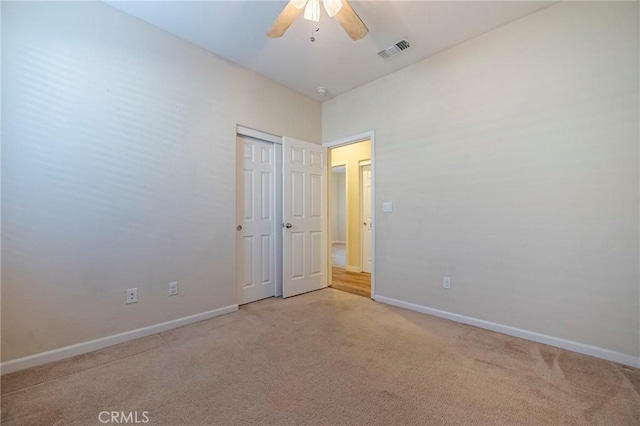 empty room with ceiling fan and light carpet