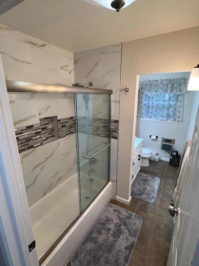 full bathroom with vanity, tile patterned flooring, bath / shower combo with glass door, and toilet