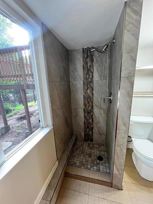 bathroom featuring a tile shower, tile patterned floors, and toilet