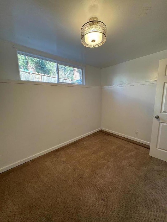 spare room featuring a wealth of natural light and dark colored carpet